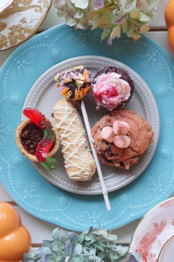 A beautifully arranged dessert plate with assorted sweets, tea, and pumpkins, set for a Tipsy Evening Tea event.