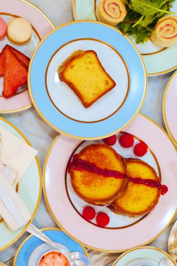 A bird's eye view of pastel colored afternoon tea ware with Laduree's iconic macarons and other Parisian treats.