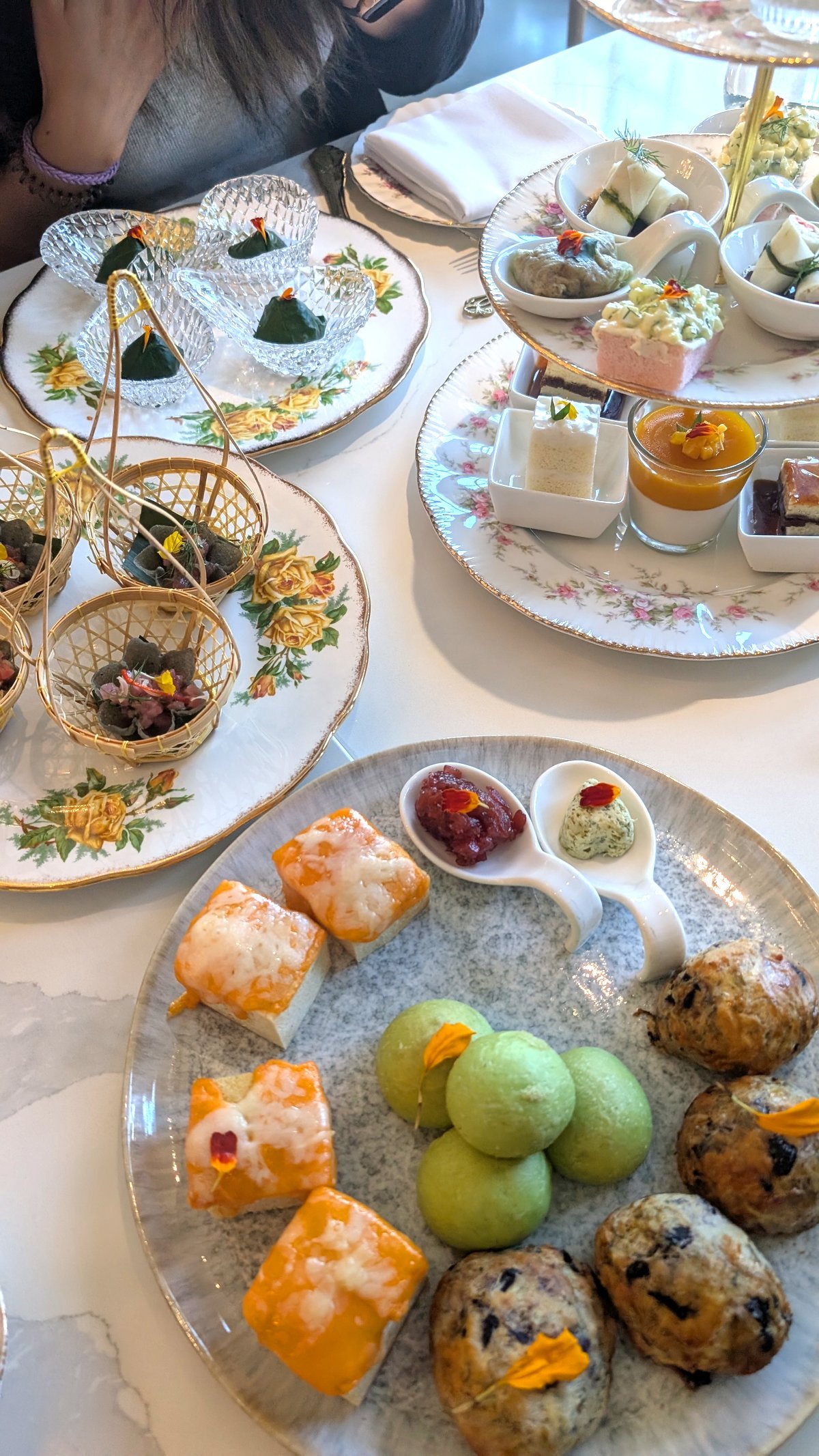 Pastries from the tea set like brioche, scones and cheese bread on a plate. 