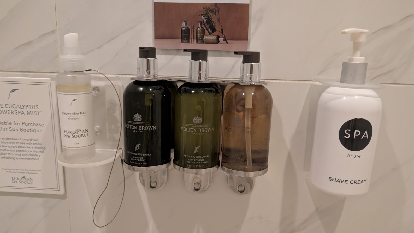 High-end body care products hung on a wall in the shower. 